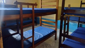 Llits superposats amb matalassos blaus en una habitació amb parets grogues i terra de rajoles.