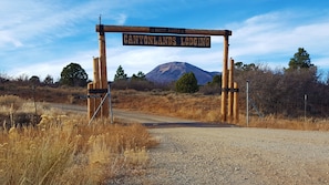 A wooden sign with "CANYONLANDS LODGING" and "A GUEST RANCH" written on it, with a mountain in the background.