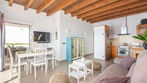 Uma sala de estar moderna com área de jantar, cozinha e uma janela grande.