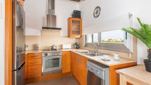 Uma cozinha moderna com armários de madeira, eletrodomésticos de aço inoxidável, forno embutido e máquina de lavar louça.