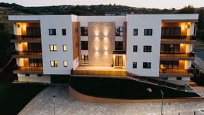 A modern multi-story hotel with a central courtyard, balconies on each floor, and a stone facade. - Gaudi Accommodation (Cluj-Napoca)
