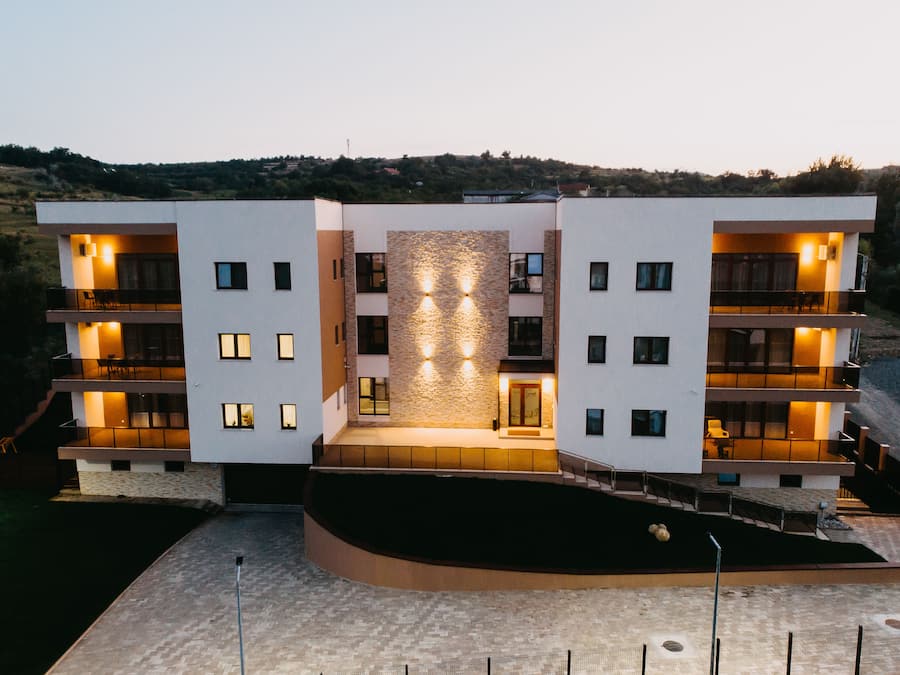 A modern multi-story hotel with a central courtyard, balconies on each floor, and a stone facade.