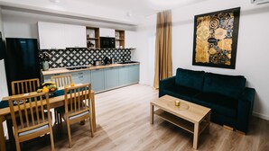 A modern living room with a dining area, a kitchen in the background, and a large abstract painting on the wall. - Gaudi Accommodation (Cluj-Napoca)