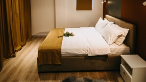 A modern bedroom with a large bed, wooden flooring, a fur rug, a nightstand, and a wall-mounted light fixture. - Gaudi Accommodation (Cluj-Napoca)