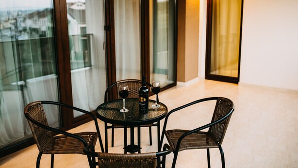 A balcony with a table and chairs, a bottle of wine, and two wine glasses. - Gaudi Accommodation (Cluj-Napoca)