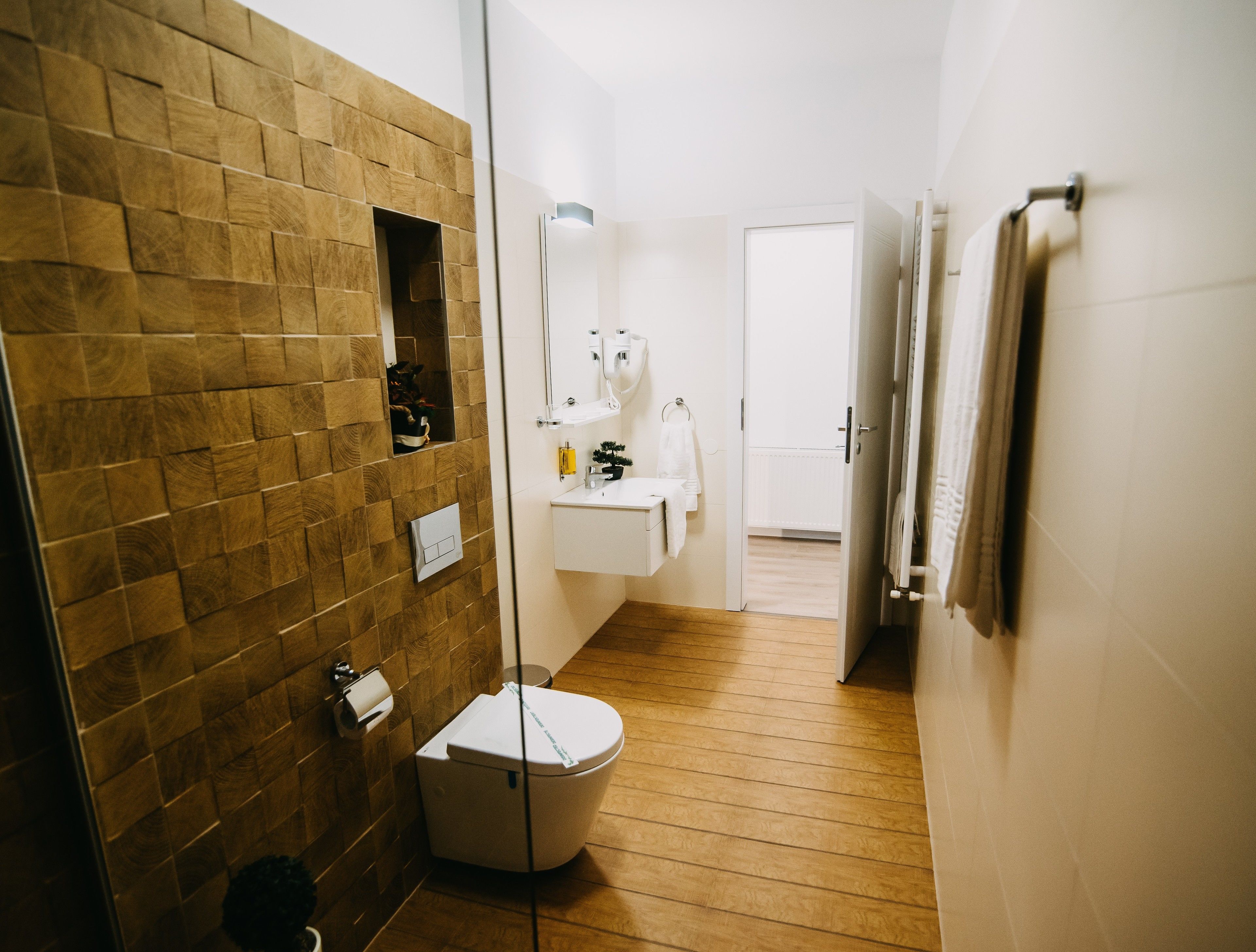 A modern bathroom with a wooden wall, a white sink, and a toilet.
