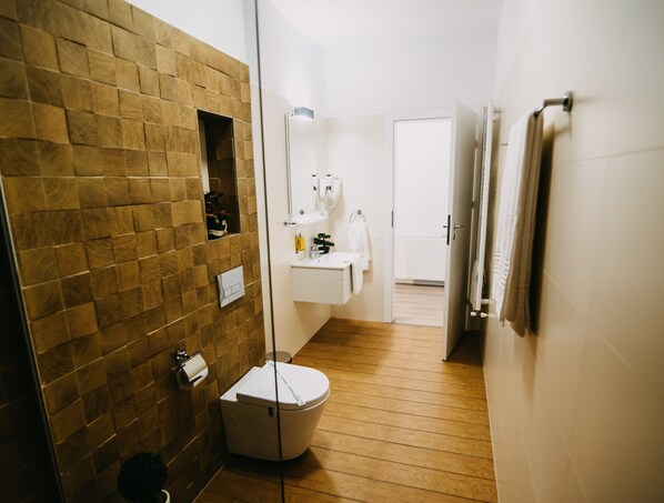 A modern bathroom with a wooden wall, a white sink, and a toilet. - Gaudi Accommodation (Cluj-Napoca)