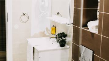 Un baño moderno con un lavamanos blanco, un espejo y una pequeña planta en maceta.
