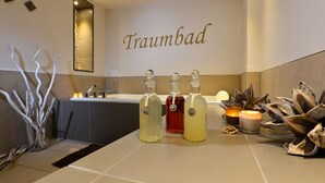 Ein Badezimmer mit Waschbecken, drei Parfümflaschen, einem Spiegel und Zimmerpflanzen.