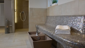 Ein modernes Badezimmer mit einem Glasmosaik-Waschbecken, einer begehbaren Dusche und einem Handtuch auf der Ablage.