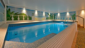 Ein Innenpool mit Kachelboden, einer Poolleiter und einer Wand mit einem tropischen Wandbild.