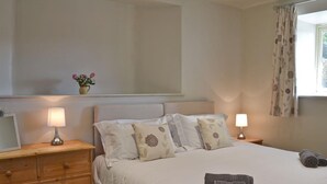 Un lit bien fait, avec des oreillers, une lampe de chevet et une commode en bois.
