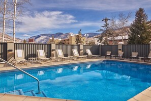 Una piscina al aire libre, sillones reclinables de piscina