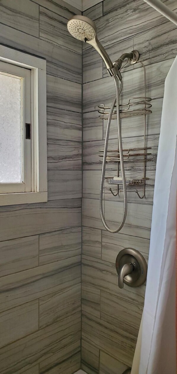 A shower with a handheld showerhead and a wall-mounted faucet.