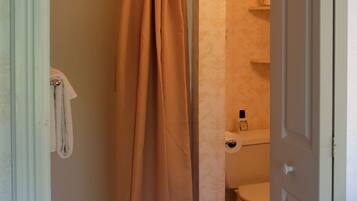 A bathroom with a shower curtain, toilet, and a towel hanging on the wall.