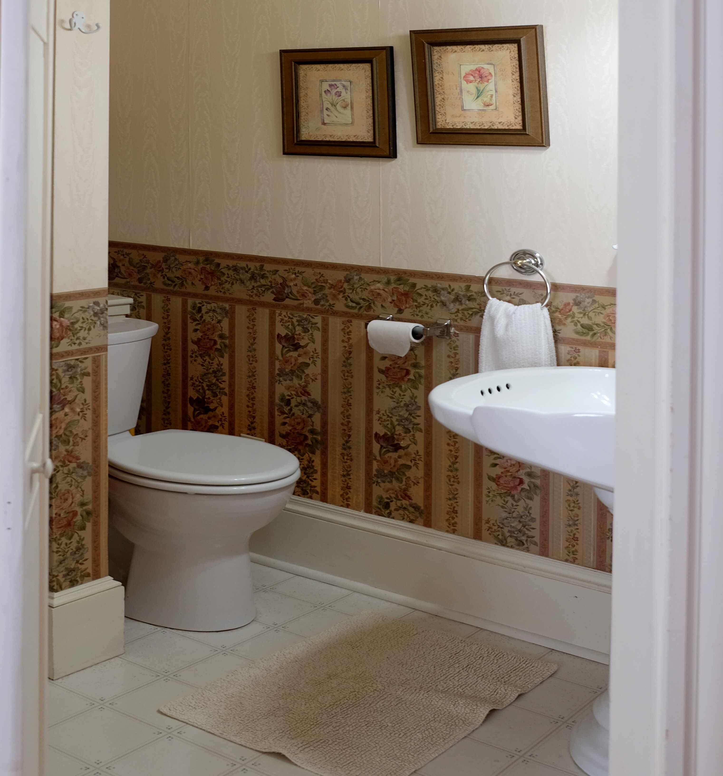 Un baño con inodoro, lavamanos y dos cuadros en la pared.