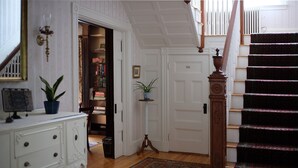 A staircase with a wooden handrail and a patterned carpet leading to a door labeled "Toilet."