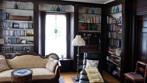 A cozy living room with a sofa, a coffee table, a fireplace, and a bookshelf filled with books.