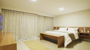 A modern hotel room with a large bed, a wooden nightstand, a bedside table, and a television. - Flat na Praia do Futuro (Fortaleza)
