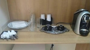 A kitchenette with a refrigerator, a coffee maker, and a tray with cups and glasses. - Flat na Praia do Futuro (Fortaleza)