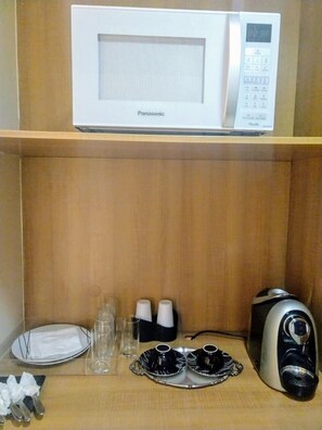 A microwave on a shelf, a toaster, and a tray with cups and a plate. - Flat na Praia do Futuro (Fortaleza)