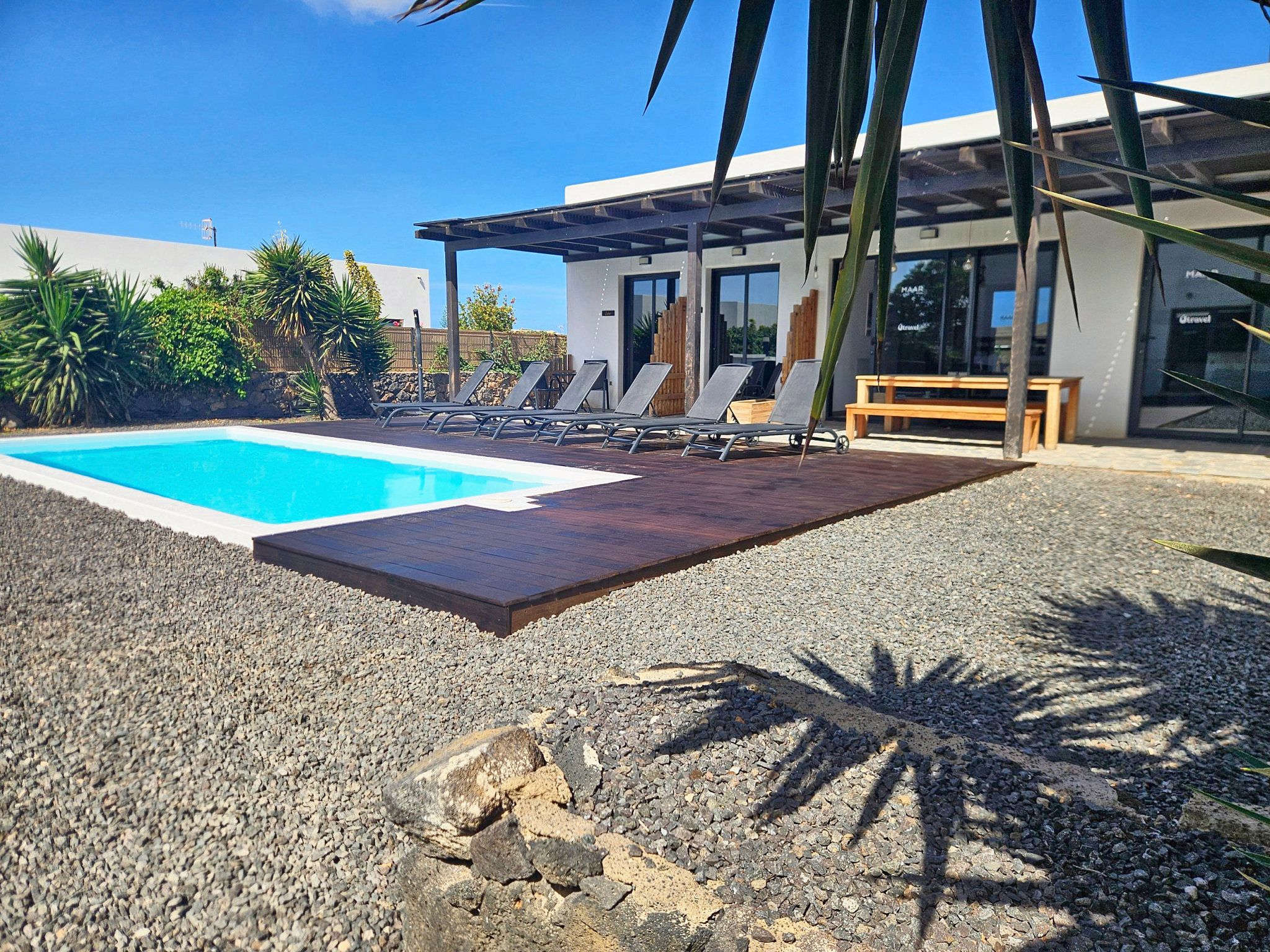 Un área de piscina moderna al aire libre con sillas de descanso y una terraza de madera.