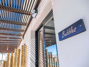 A building entrance with a sign reading 'Bubbles' and a wooden slatted ceiling structure. - MAAR House (La Oliva)