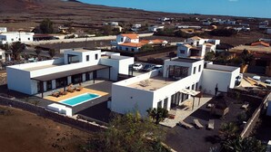 A modern residential area with white buildings, a swimming pool, and a clear view of the surrounding landscape. - MAAR House (La Oliva)