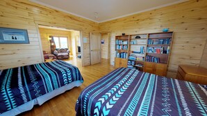 A room with two beds, a bookshelf, and a door leading to another room. - Mustang Mesa Amazing Views (Blanding)