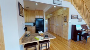 A compact kitchen with wooden cabinets, a black refrigerator, and a dining area with a piano. - Mustang Mesa Amazing Views (Blanding)