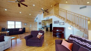 A spacious living area with a wooden ceiling, a piano, and a staircase leading to an upper level. - Mustang Mesa Amazing Views (Blanding)