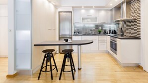 Una cocina moderna con una isla central, dos taburetes de bar, un microondas y una estufa.