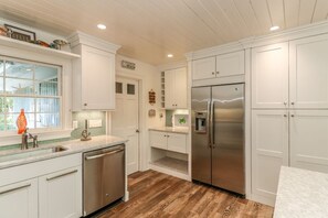 Une cuisine avec des meubles blancs, un réfrigérateur en acier inoxydable et un plancher en bois.