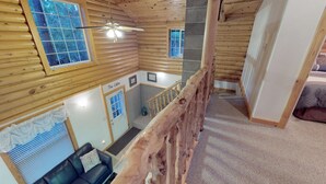 A cabin interior with a wooden interior, a ceiling fan, a staircase, and a couch with a cushion. - The Cabin at Lydias Canyon (Glendale)