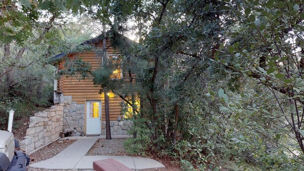 A rustic log cabin with a stone foundation, a wooden door, and a pathway leading to the entrance. - The Cabin at Lydias Canyon (Glendale)