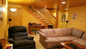 Ein Wohnzimmer mit Sofa, Sessel und einer Holztreppe.