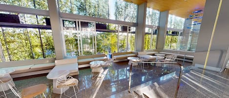 A modern interior with large windows, a seating area, and a polished floor.