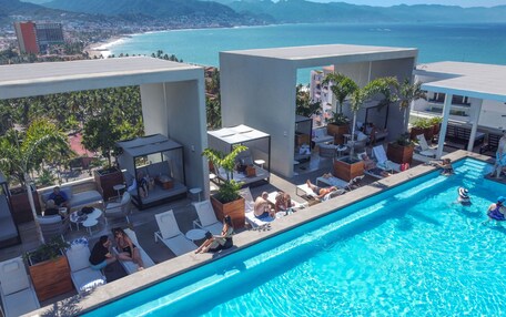 A rooftop pool area with lounge chairs and a view of the ocean.