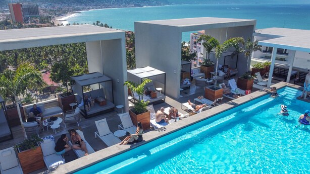 Área de piscina en la azotea con sillones de descanso y vista al océano.