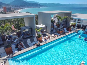 Zona d'una piscina al terrat amb gandules i vistes a l'oceà.