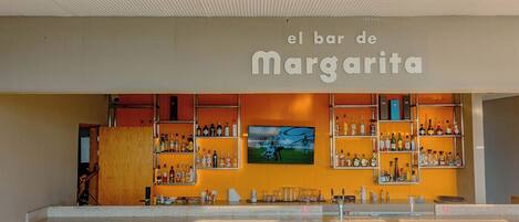 A bar named 'el bar de Margarita' with shelves of bottles and a television screen.