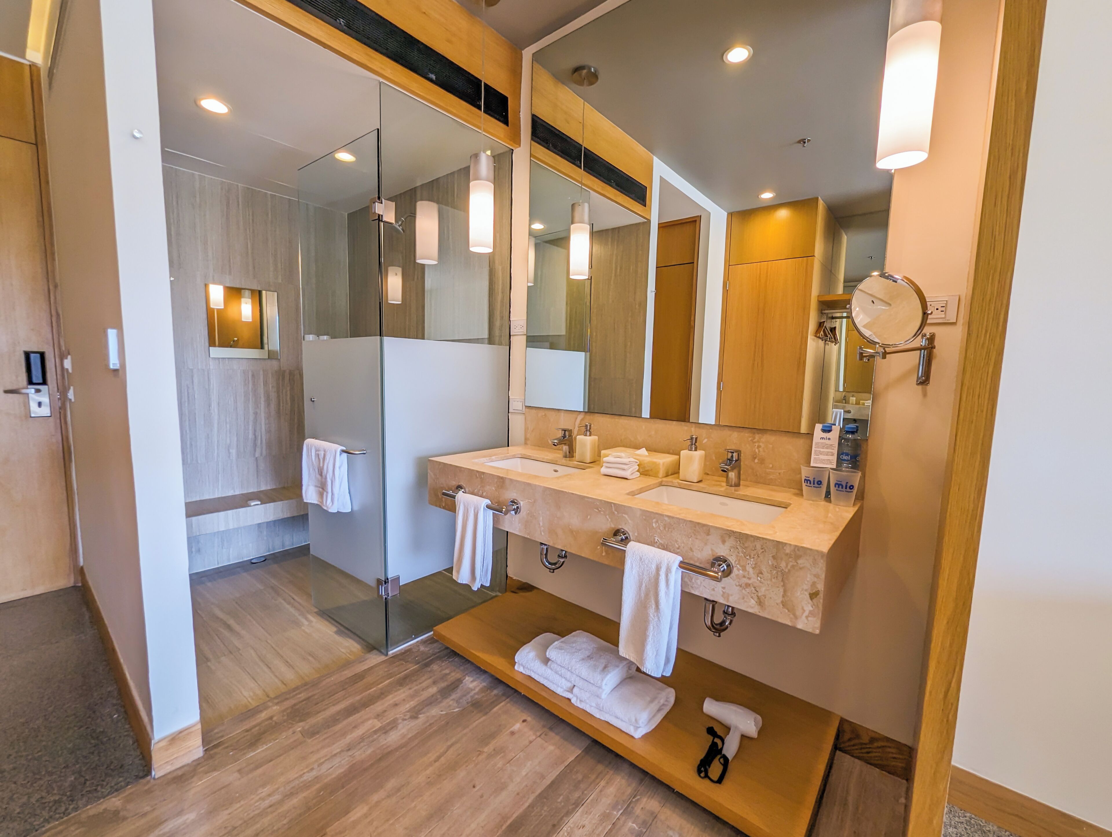 Un baño moderno con cabina de ducha de vidrio, tocador doble y espejo integrado.