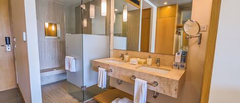 Un baño moderno con cabina de ducha de vidrio, tocador doble y espejo integrado.