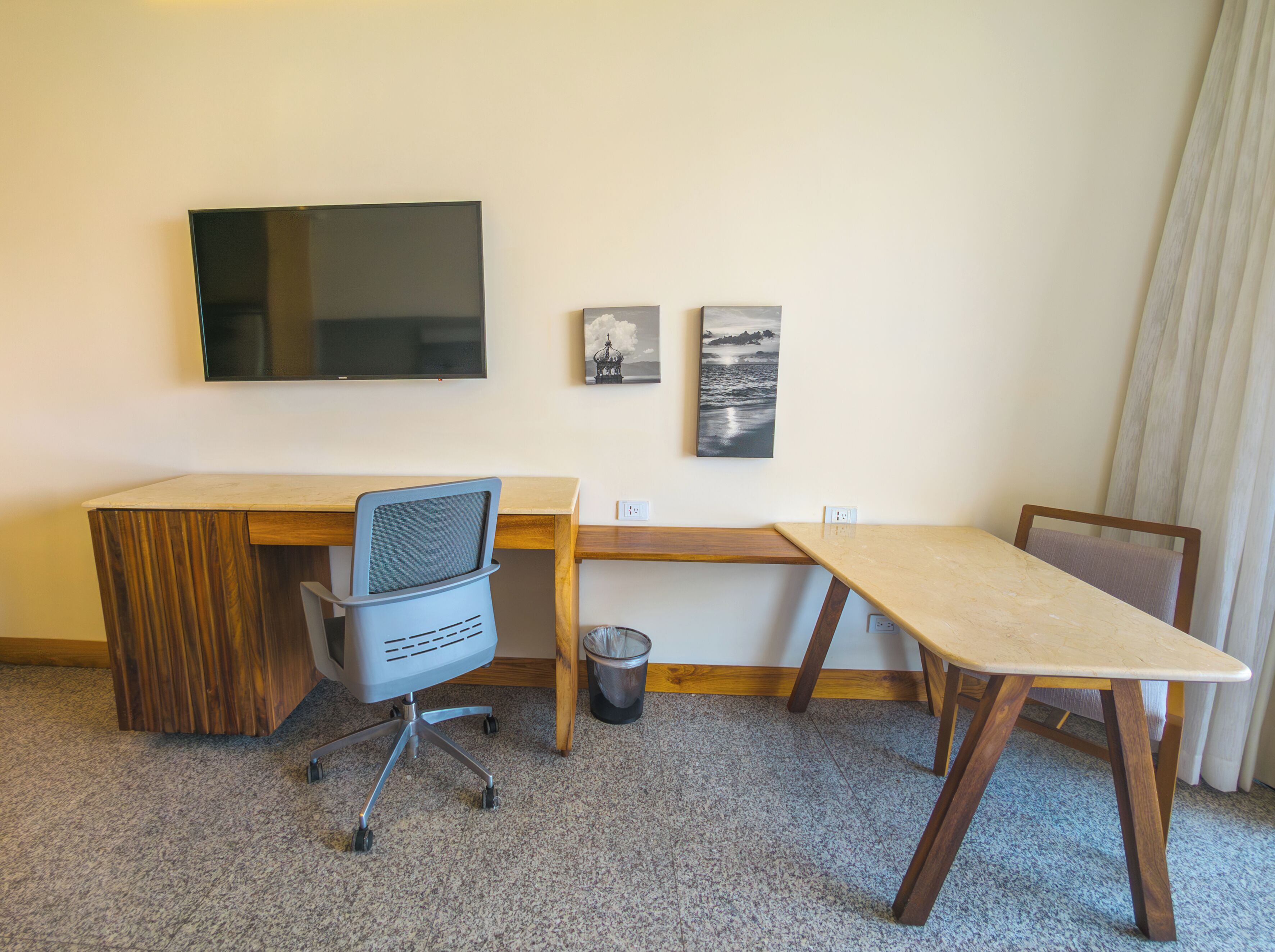 Habitación de hotel con escritorio, silla, televisor y dos cuadros en la pared.