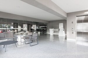 A modern waiting area with glass walls, a reception desk, and a polished floor.