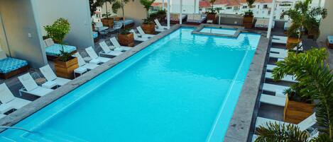 A rooftop pool with multiple lounge chairs and planters.