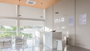 Un moderno hall de hotel con mostrador de recepción, zona de estar y ventanas amplias que ofrecen vistas al exterior con vegetación.