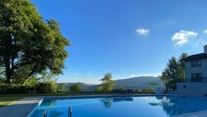 A swimming pool with a clear view of mountains in the background, surrounded by trees and a building. - Chaletde montagne indépendant en Alsace Massif du Champ du Feu - Ski resort  (Bellefosse)