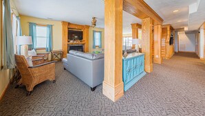 Un vaste espace de vie doté d’une cheminée, d’un grand téléviseur et d’un coin repas avec un buffet bleu.