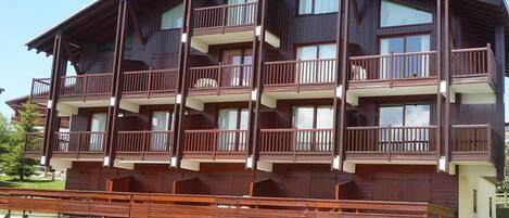 A multi-story wooden building with balconies, likely a hotel or apartment complex.
